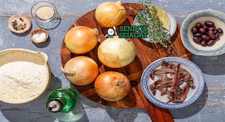 Bahan-bahan untuk membuat Pissaladière, termasuk bawang bombay, ikan teri, dan zaitun hitam