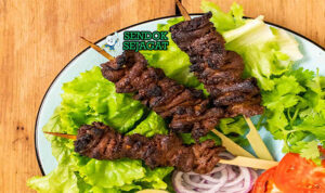 Nigerian Suya dengan daging sapi, bawang merah, dan tomat