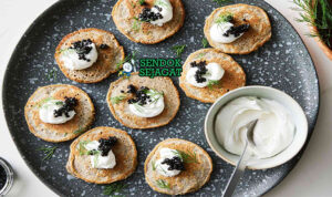 Blini dengan krim asam dan kaviar di piring saji