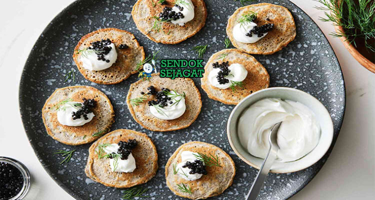 Blini dengan krim asam dan kaviar di piring saji