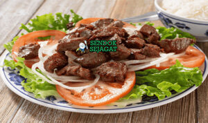 Bò Lúc Lắc dengan daging tumis dan bawang bombay di piring saji