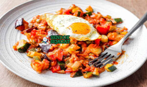 Pisto Manchego dengan tomat dan zucchini di piring saji