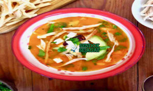 Sopa Azteca dengan tortilla renyah dan hiasan alpukat di mangkuk saji