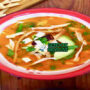 Sopa Azteca dengan tortilla renyah dan hiasan alpukat di mangkuk saji