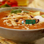 Sopa de Tortilla dengan tortilla renyah dan hiasan alpukat di mangkuk saji