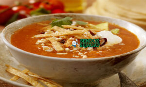 Sopa de Tortilla dengan tortilla renyah dan hiasan alpukat di mangkuk saji