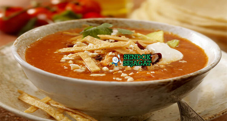 Sopa de Tortilla dengan tortilla renyah dan hiasan alpukat di mangkuk saji