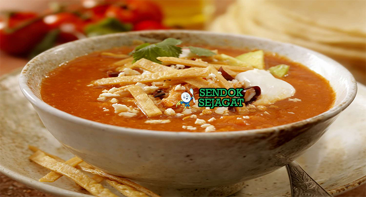Sopa de Tortilla dengan tortilla renyah dan hiasan alpukat di mangkuk saji