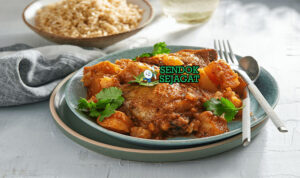 Cape Malay Curry ayam rempah aprikot yogurt atas nasi di mangkuk saji