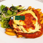 Chicken Parma ayam schnitzel topping keju leleh dengan chips di piring saji