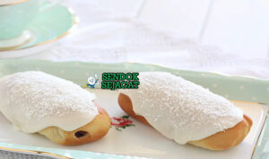 Finger Bun Roti Manis Glasur Khas Australia Finger Bun roti manis dengan glasur merah muda dan kelapa di piring saji