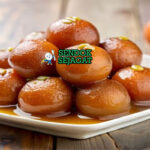 Gulab Jamun bola susu berendam sirup dengan pistachio di mangkuk saji