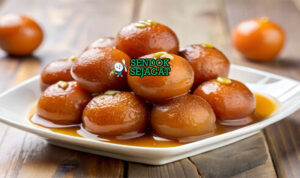 Gulab Jamun Bola Susu Sirup M= Mawar Khas India Gulab Jamun bola susu berendam sirup dengan pistachio di mangkuk saji