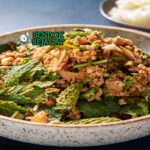Laab Moo dengan daging babi pedas dan ketan di piring saji