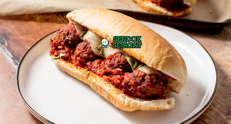 Meatball Sub Cheesy Saucy Meatball Sub roti sub daging bola saus keju meleleh potong dua di piring saji