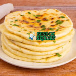 Naan roti pipih lembut gelembung ghee dengan curry di piring saji