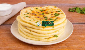 Naan Roti Pipih Gurih Khas India Naan roti pipih lembut gelembung ghee dengan curry di piring saji