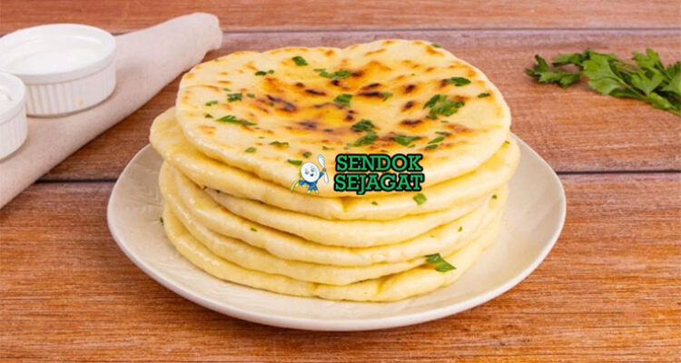 Naan roti pipih lembut gelembung ghee dengan curry di piring saji