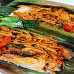 Nasi Bakar Ayam Suwir dengan daun pisang dan lalapan di piring saji