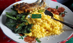 Nasi Jagung Campur Ikan Asap Khas Madura Nasi Jagung campur ikan asap dengan sambal dan kangkung di piring saji