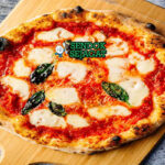Pizza Margherita tipis gelembung mozzarella meleleh basil segar di piring saji