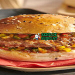 Pljeskavica burger daging dengan roti somun dan ajvar di piring saji