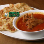 Roti Canai renyah lapis dengan saus kari ayam di piring saji