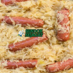 Sauerkraut kubis fermentasi dengan sosis di piring saji