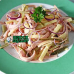 Schweizer Wurstsalat dengan sosis dan keju di piring saji
