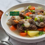 Sop Buntut Kuah Bening dengan buntut sapi dan sayuran di mangkuk saji