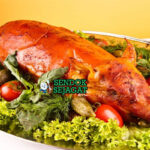 Spanferkel babi panggang kulit renyah dengan sauerkraut di piring saji