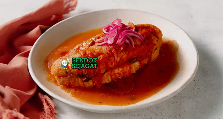 Torta Ahogada dengan roti isi daging dan saus pedas di piring saji