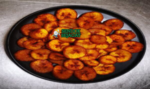Alloco pisang kepok goreng golden tabur cabe saus tomat pedas di piring anyaman