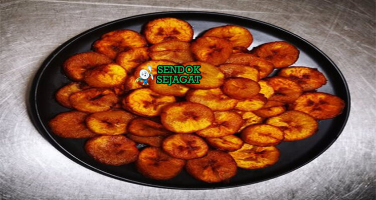 Alloco pisang kepok goreng golden tabur cabe saus tomat pedas di piring anyaman