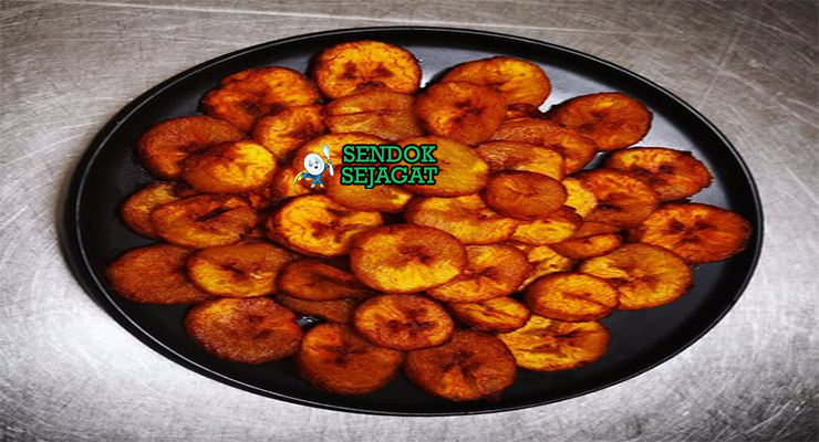 Alloco pisang kepok goreng golden tabur cabe saus tomat pedas di piring anyaman