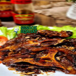 Buntut Bakar potongan gosong kecap manis wangi dengan sambal lalapan di piring saji