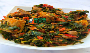 Efo Riro Pedas Kaya Rasa Khas Yoruba Efo Riro hijau cerah kuah minyak sawit daging sapi kpomo stockfish ikan asap di mangkuk besar