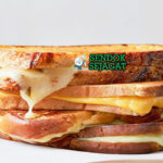 Grilled Cheese Sandwich roti garing keju meleleh potong diagonal dengan sup tomat