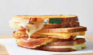 Grilled Cheese Sandwich roti garing keju meleleh potong diagonal dengan sup tomat