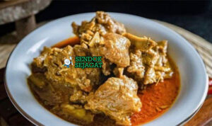 Gulai Kambing kuah santan kuning pekat daging empuk bawang goreng emping di mangkuk saji