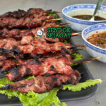 Moo Ping tusuk babi karamel mengkilap sticky rice nam jim jaew timun di daun pisang