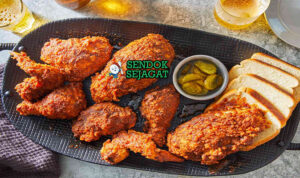 Nashville Hot Chicken ayam golden pedas saus cayenne roti acar di piring saji