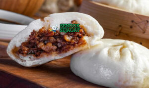 Nikuman Juicy Lembut Khas Konbini Jepang Nikuman kukus putih mengkilap isi daging babi jamur kuah juicy cap merah di rak bambu