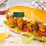 Shrimp Po' Boy sandwich udang goreng tinggi remoulade lettuce tomato di kertas lilin