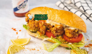 Shrimp Po' Boy sandwich udang goreng tinggi remoulade lettuce tomato di kertas lilin