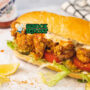 Shrimp Po' Boy sandwich udang goreng tinggi remoulade lettuce tomato di kertas lilin