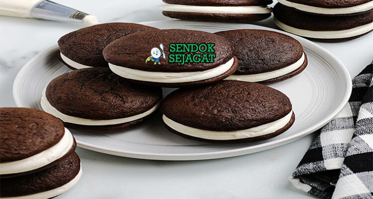 Whoopie Pie cokelat hitam sandwich filling marshmallow putih tebal di atas piring vintage