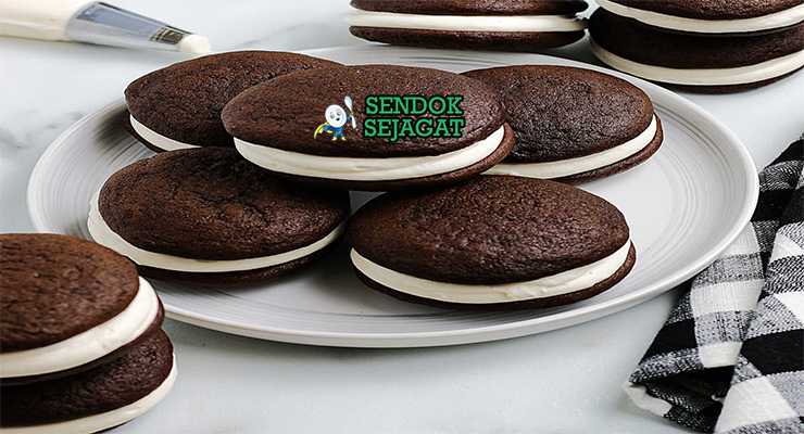 Whoopie Pie cokelat hitam sandwich filling marshmallow putih tebal di atas piring vintage