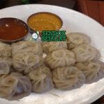 Momo dumpling kukus isi ayam achar tomat pedas sesame timur piring kayu Nepal