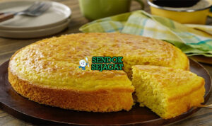 Pan de Elote Lembut Manis Khas Puebla Mexico Pan de Elote potong kotak golden moist jagung utuh susu kental cinnamon powder di piring tanah liat